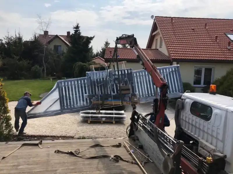 Rozładunek elementów ogrodzenia z użyciem dźwigu podczas montażu